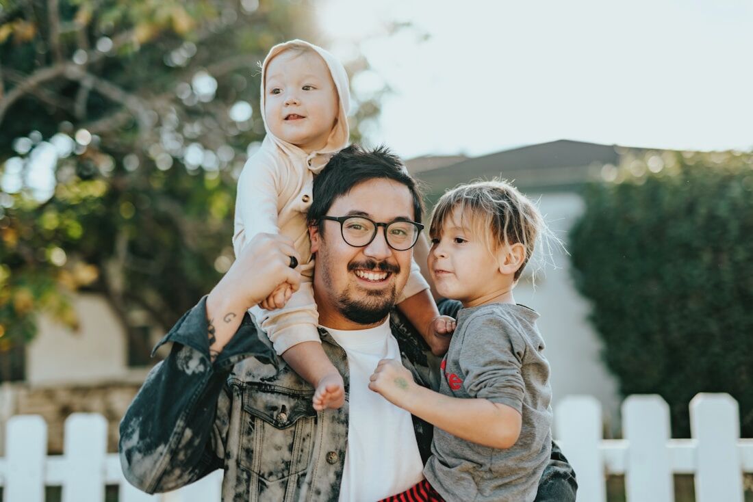 A father laughing with his two young children in the garden
