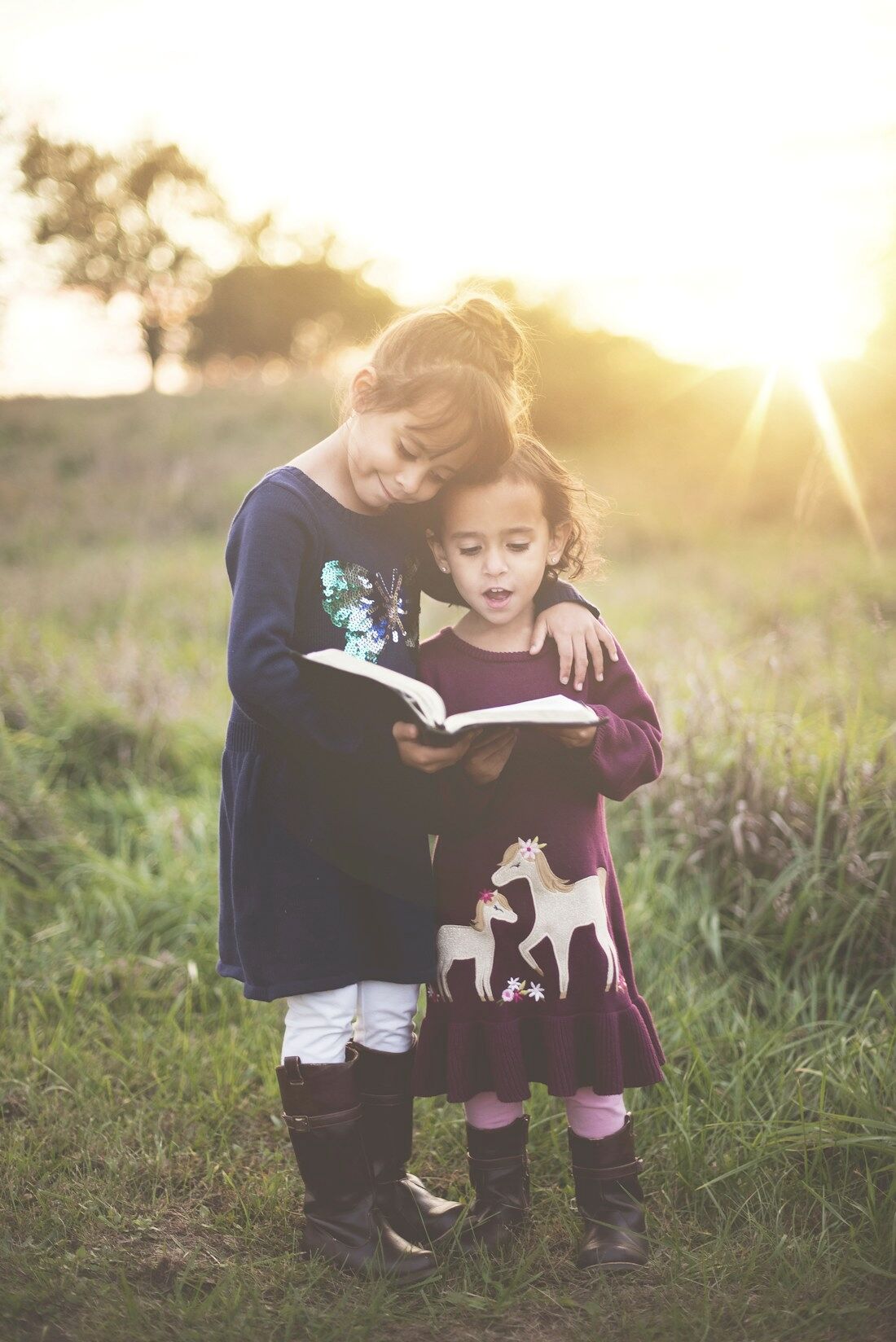 Two children reading a storybook together in a golden autumn field