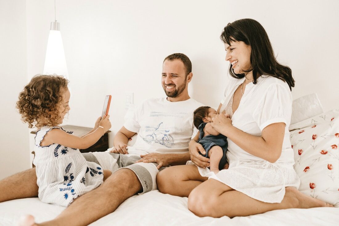 A young family relaxing together on a white bed in matching pale sleepwear
