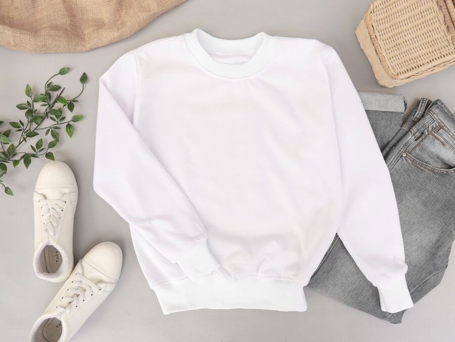 A neutral flat-lay of a folded white sweater, jeans and canvas shoes